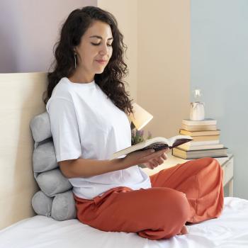 Frau liest im Bett mit dem Rollow InnovaGoods Multifunktions-Kissen zur Rückenunterstützung