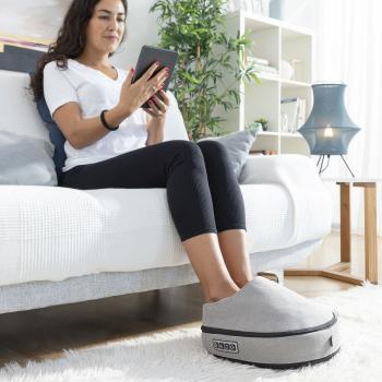 Frau nutzt das Shiatsu-Thermo-Massagegerät Futsa InnovaGoods auf dem Sofa für eine wohltuende Fußmassage