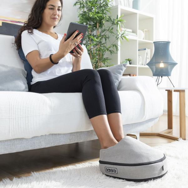 Frau nutzt das Shiatsu-Thermo-Massagegerät Futsa InnovaGoods auf dem Sofa für eine wohltuende Fußmassage